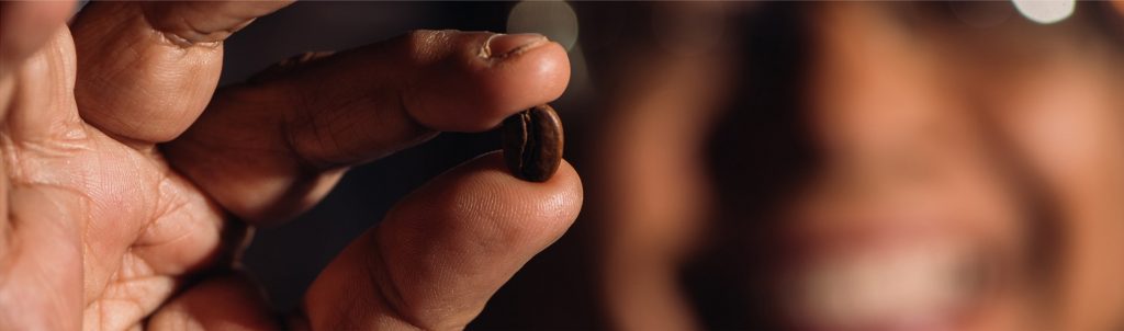 chicco di caffè tra due dita